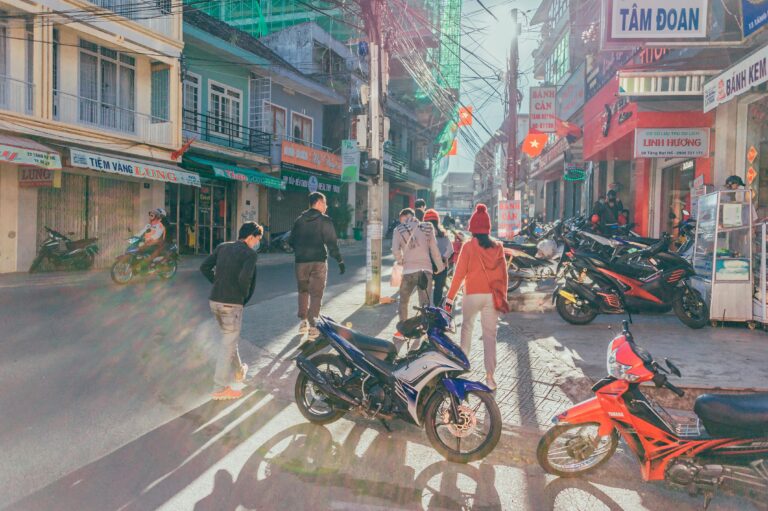 Projects 4 Vibrant street filled with motorbikes and pedestrians in a lively town setting.