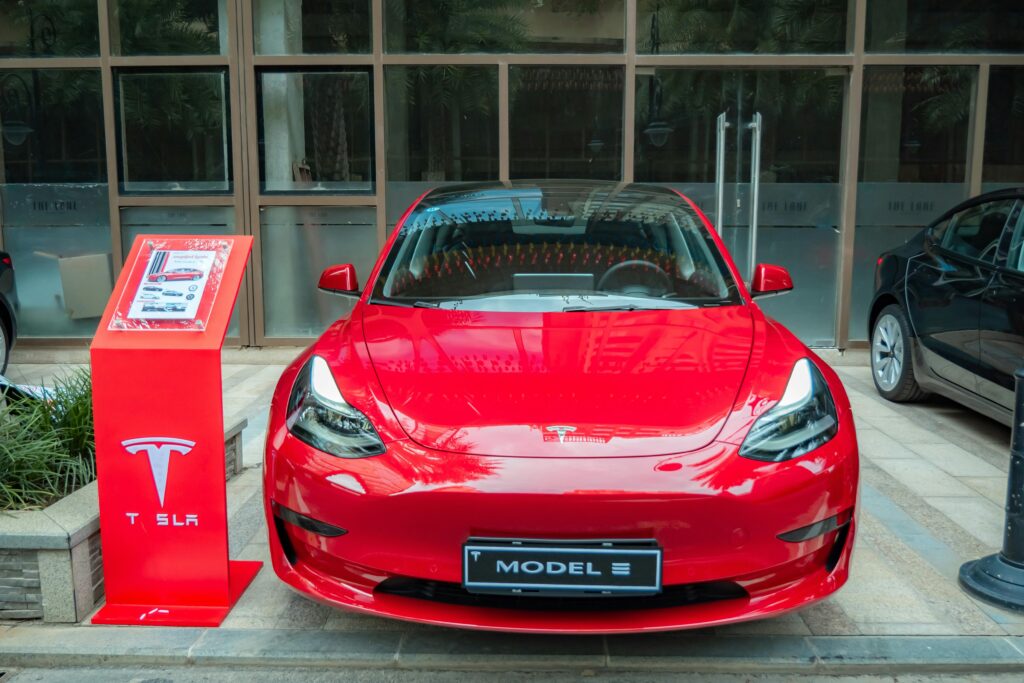 Real Cost of RangeA stylish red Tesla Model 3 parked in an urban area, showcasing its sleek design and luxury features.