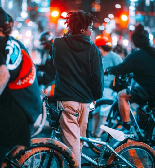Projects 7 Group of teenagers biking in a vibrant city with neon lights at night.